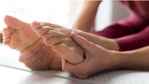 Close-up of legs and hands stretching on a mat