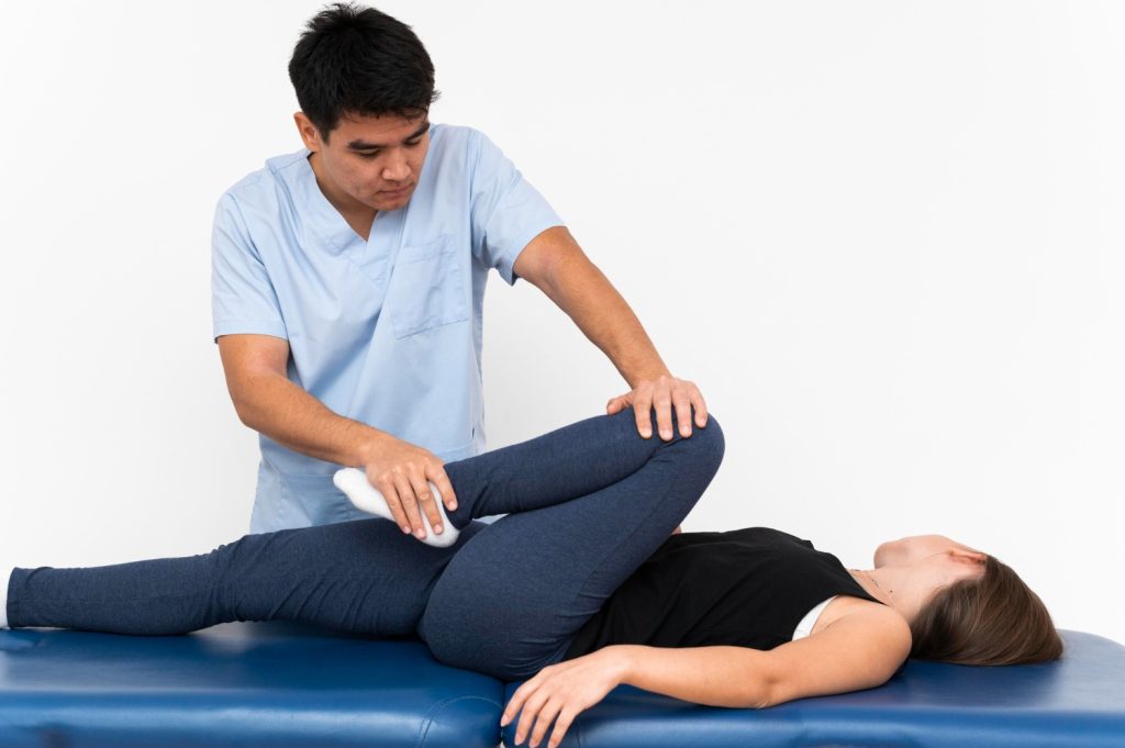 Chiropractor guiding female patient through leg exercises
