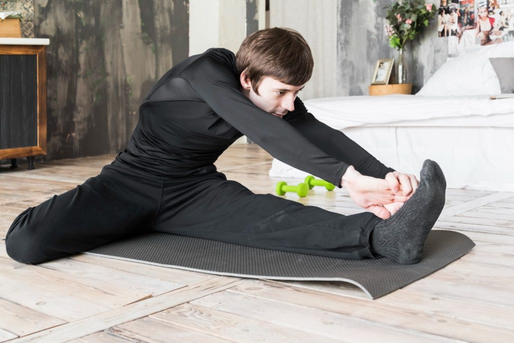 Man doing hamstring stretch on mat to relieve back strain