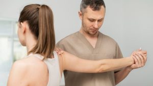 Healthcare professional Kelowna Chiropractor evaluating and examining a patient’s shoulder during a clinical assessment