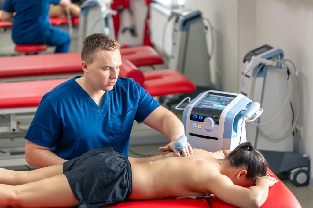 Chiropractor assessing and treating a patient's back during a therapy session.