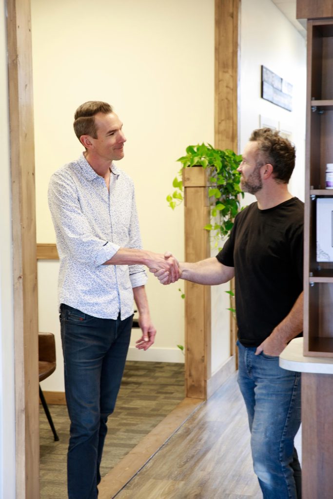 Man shaking hands with a chiropractor inside a chiropractic clinic.
