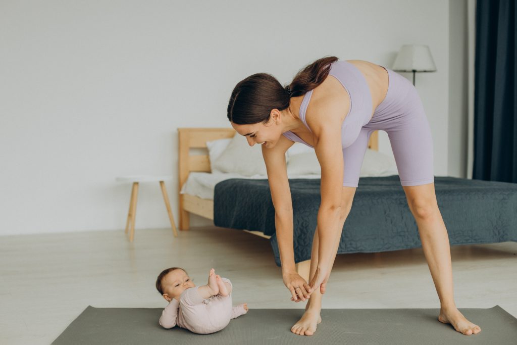 Mother with her baby daughter practice yoga at home